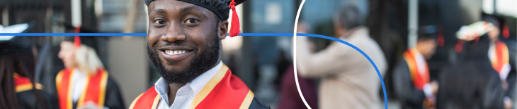 Smiling graduate in cap and gown at an outdoor graduation ceremony with peers in the background