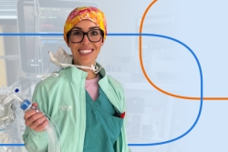 Smiling healthcare professional in scrubs and a surgical cap holding medical equipment in a clinical setting.