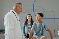 Physician speaks with teenage patient and parent in a clinic exam room; ‘AGREE TO AGREE’ graphic in the corner.