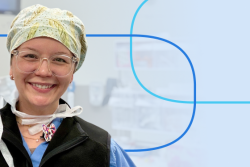 Smiling healthcare professional in scrubs and a patterned surgical cap wearing clear-framed glasses