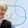 Smiling healthcare professional in scrubs and a patterned surgical cap wearing clear-framed glasses