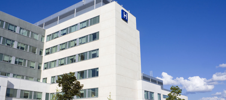 Modern hospital building with large windows and a blue sky background