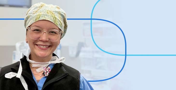 Smiling healthcare professional in scrubs and a patterned surgical cap wearing clear-framed glasses